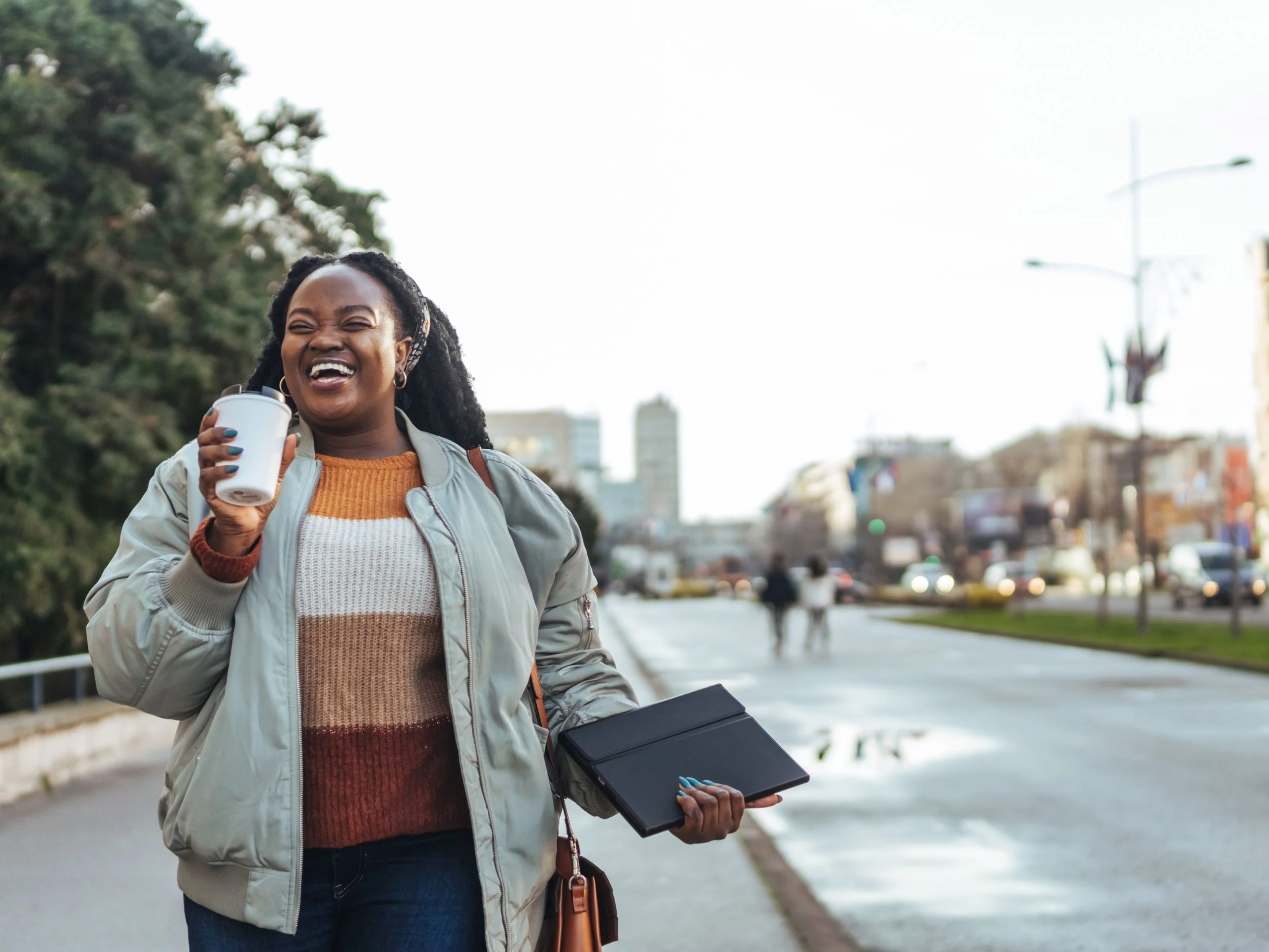 Mujer sonriente caminando por la calle con café para llevar