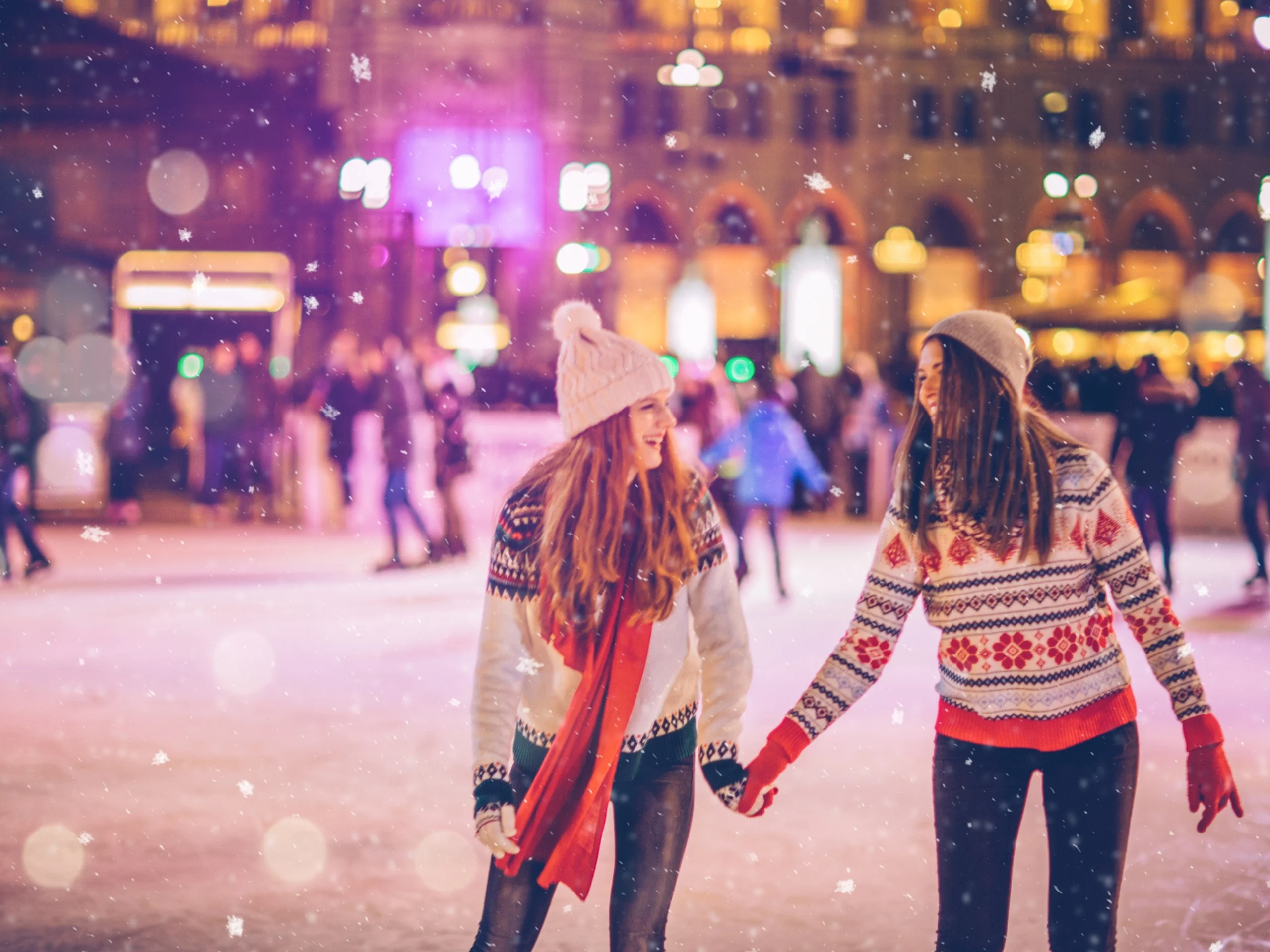 Dos chicas patinando en pista de hielo en Navidad