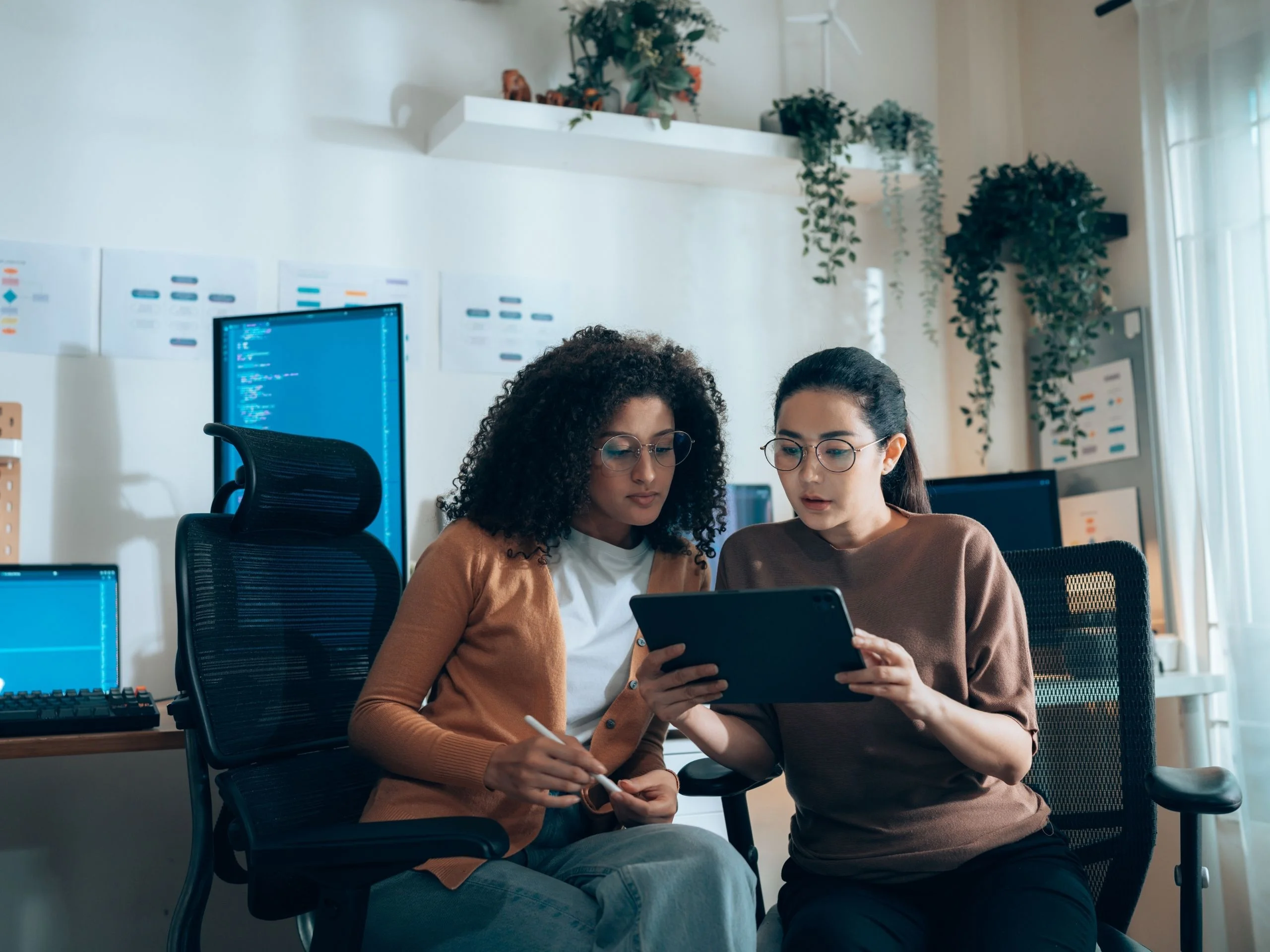 Dos mujeres profesionales revisando código en una tablet