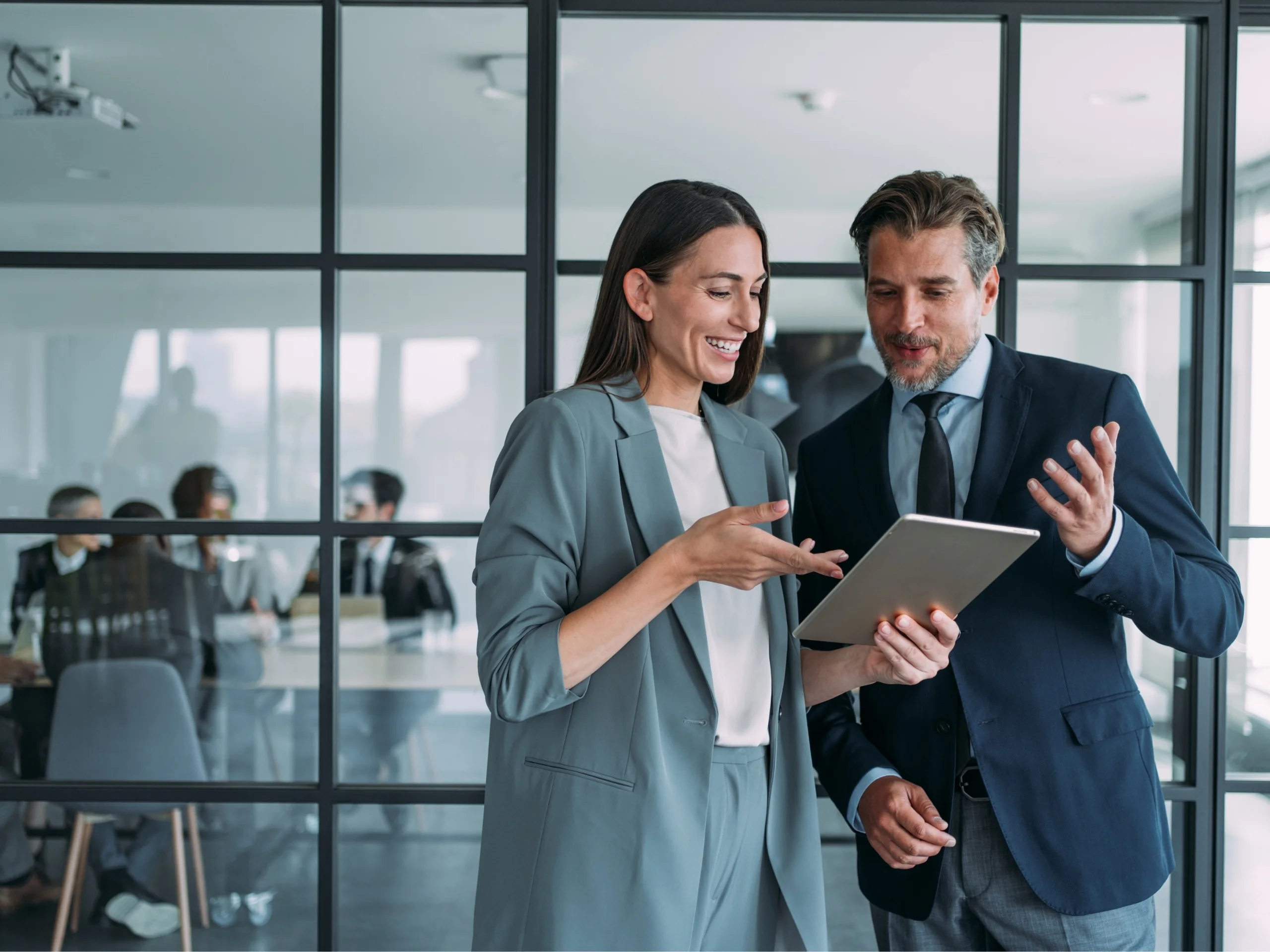 Mujer y hombre en entorno laboral mirando una tablet