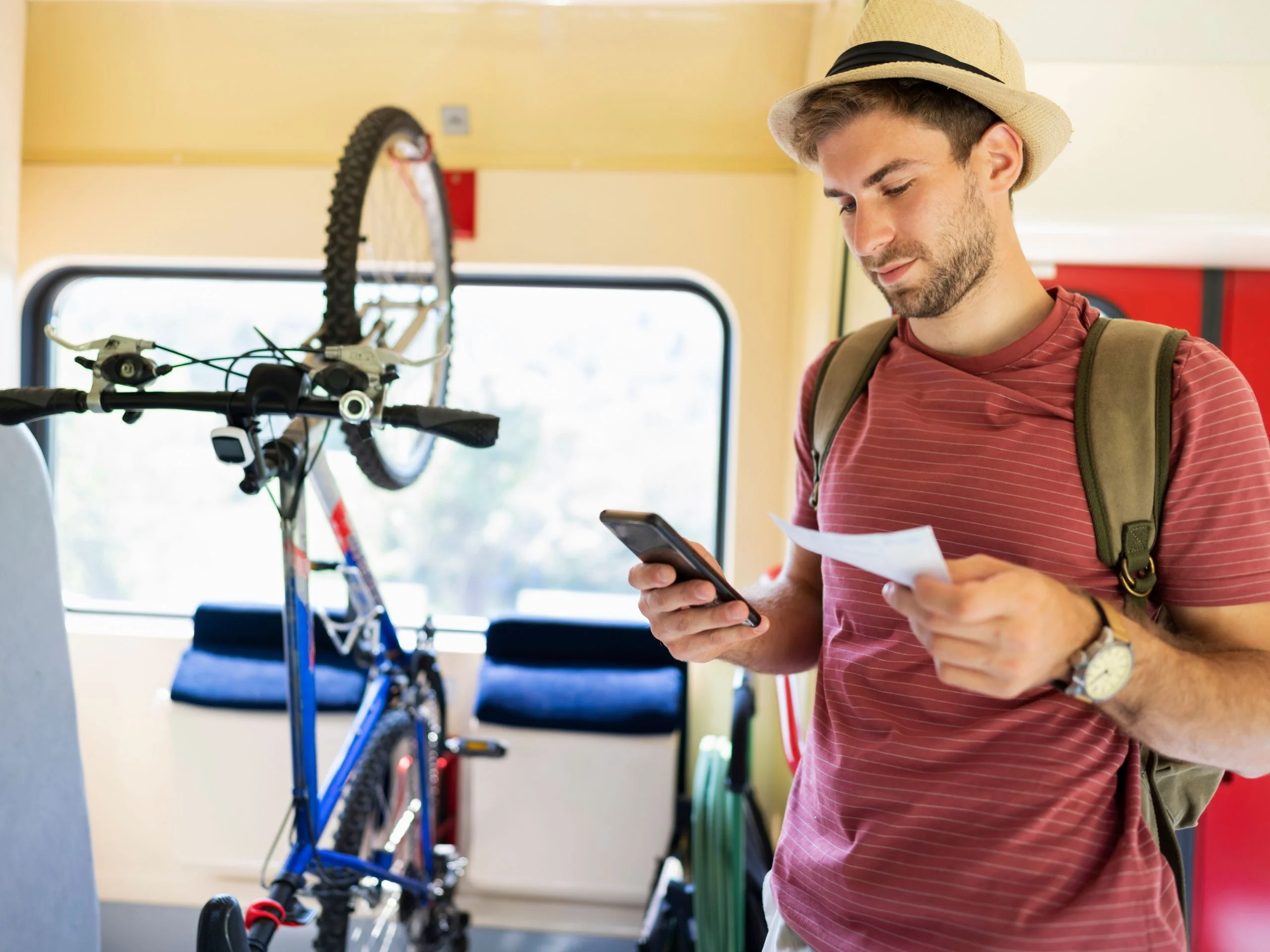 Hombre joven en tren con bici apoyada en la pared