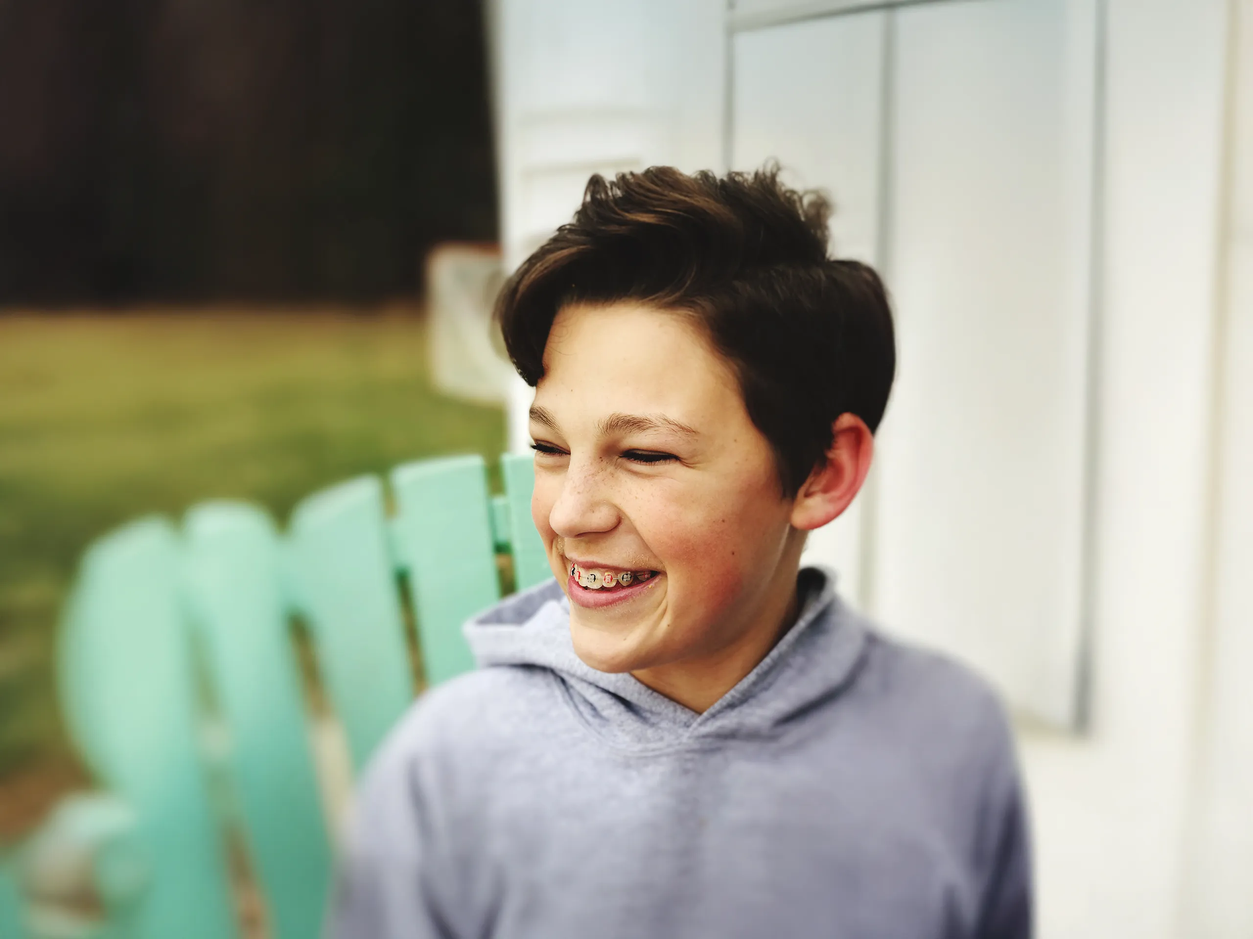 Niño sonriente con aparatos ortopédicos sentado en una silla.