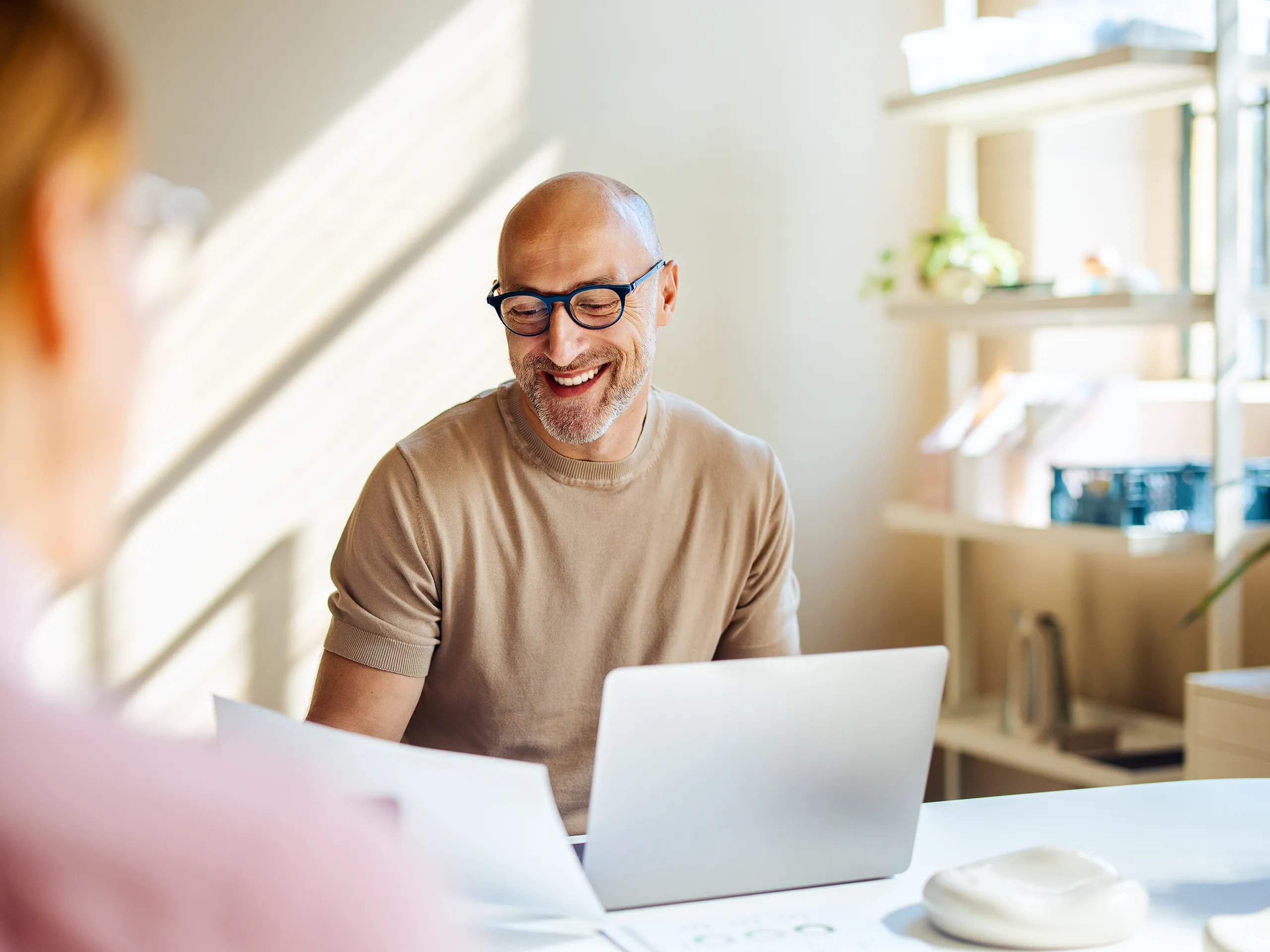 Hombre con gafas sonriendo mientras trabaja en su portátil