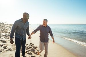 Pareja homosexual de hombres de mediana edad paseando por una playa