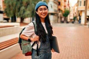 Mujer asiática yendo a trabajar, en la calle, sonriendo a cámara