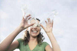 Una chica sonríe sosteniendo dos botellas de vidrio