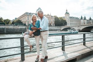 Pareja de hombre y mujer blancos de la tercera edad posando sonrientes frente al Sena