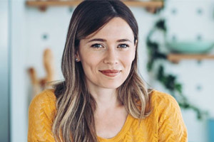 Chica blanca con blusa amarilla sonriendo a cámara